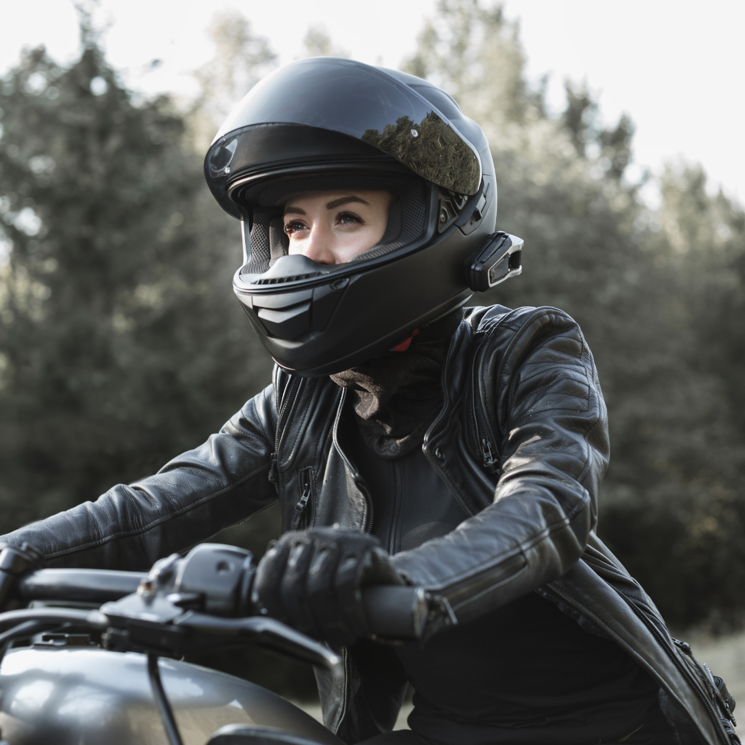 A woman confidently dons a helmet on her motorcycle, understanding the worth it. of protective gear while riding.